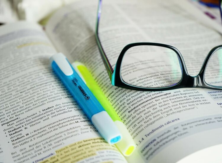 offenes Buch mit Textmarker und Brille drauf