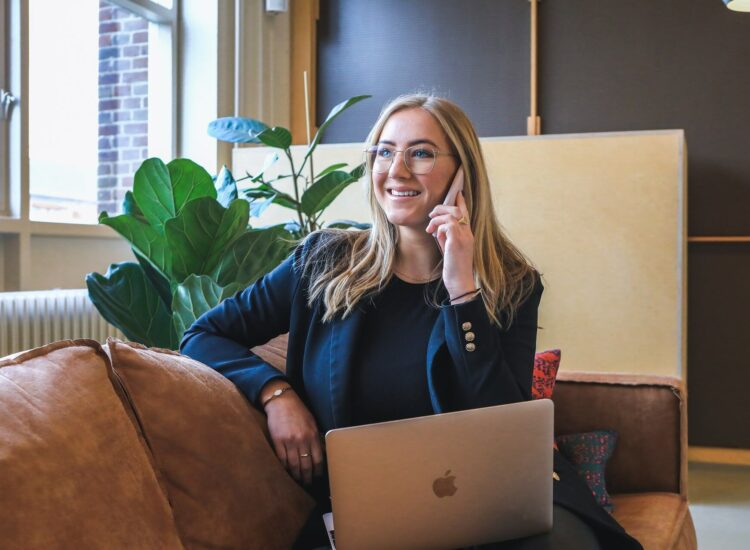 Frau telefoniert - vor ihr ist ein Laptop